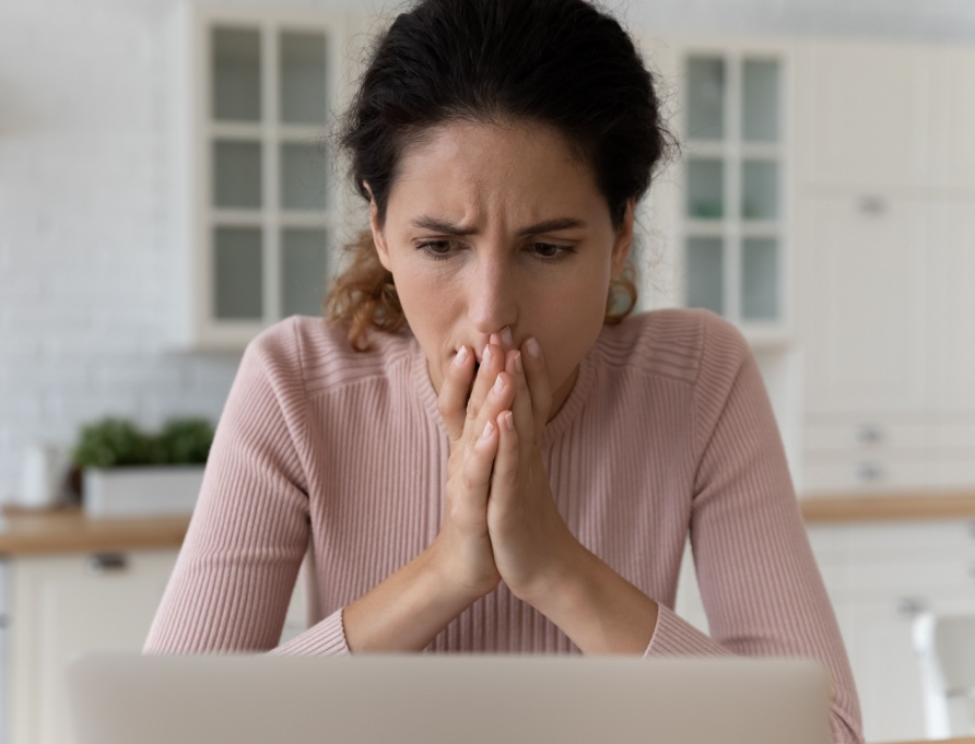 A woman looks at her laptop in shock.
