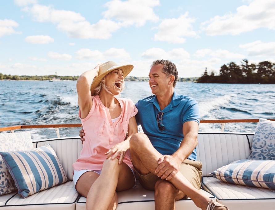A couple in their 50s laughing on a boat together.