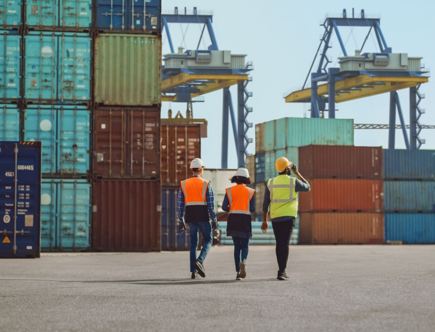 Workers walking through a shipping cargo container terminal depot