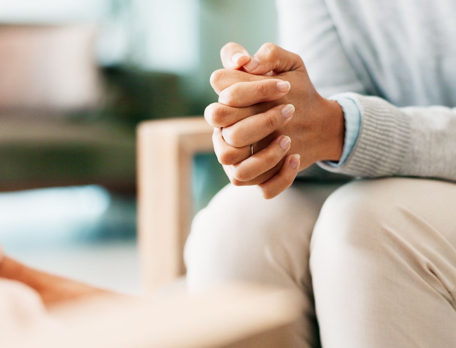 A woman sitting with her hands clasped.