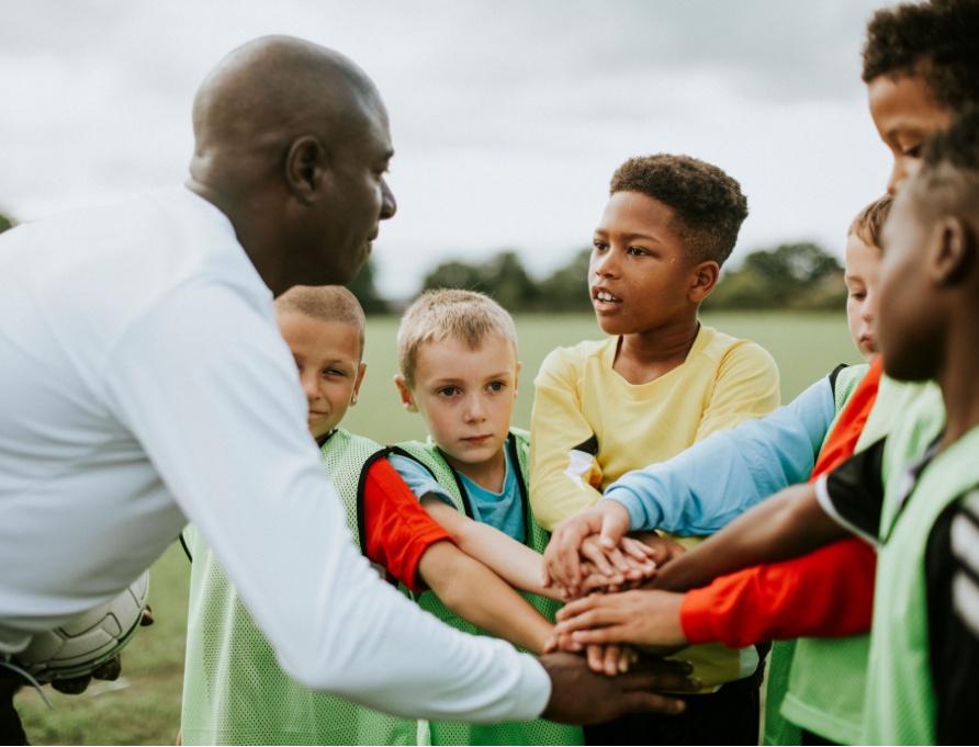 A man coaching a junior football team.
