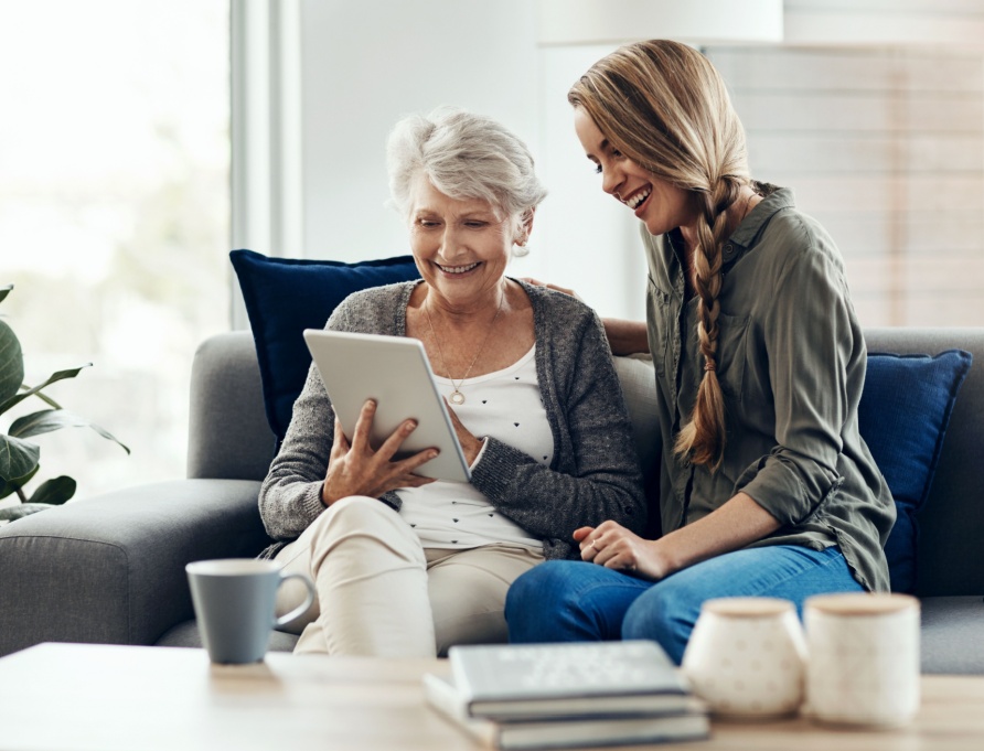 A woman showing her adult daughter something on a tablet.