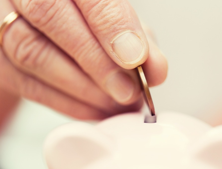 A person putting a coin into a money box.
