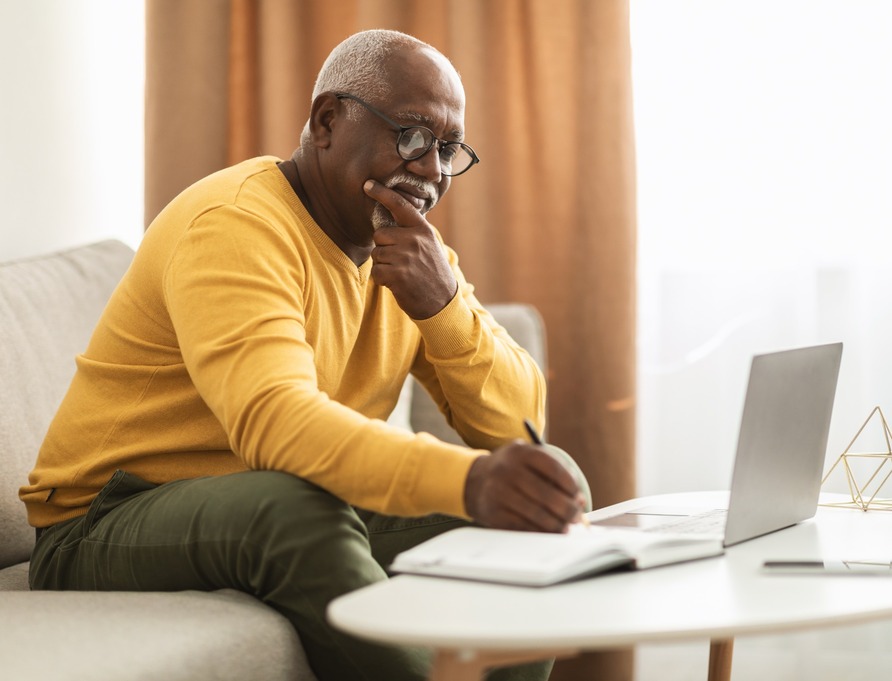 A man writing notes at a coffee table.